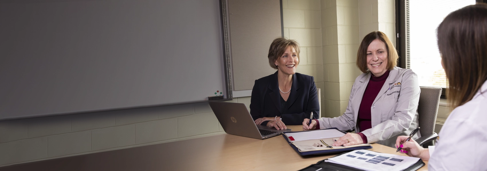 Women sitting at a table with a laptop and folders