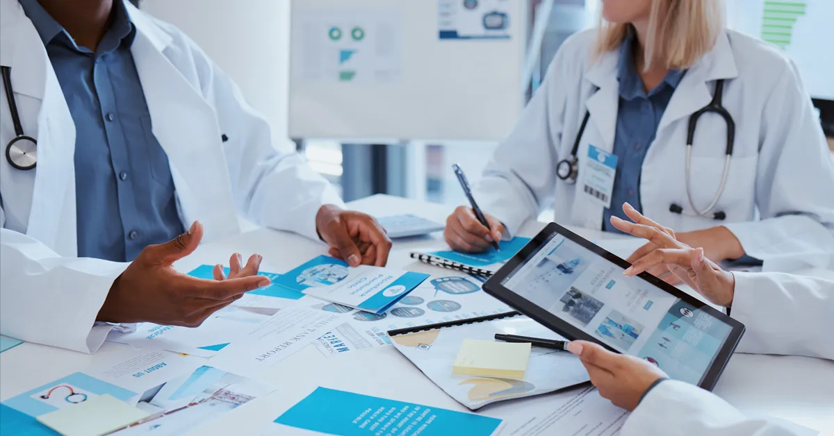 Three providers reviewing lots of printed materials and one holds a tablet device.