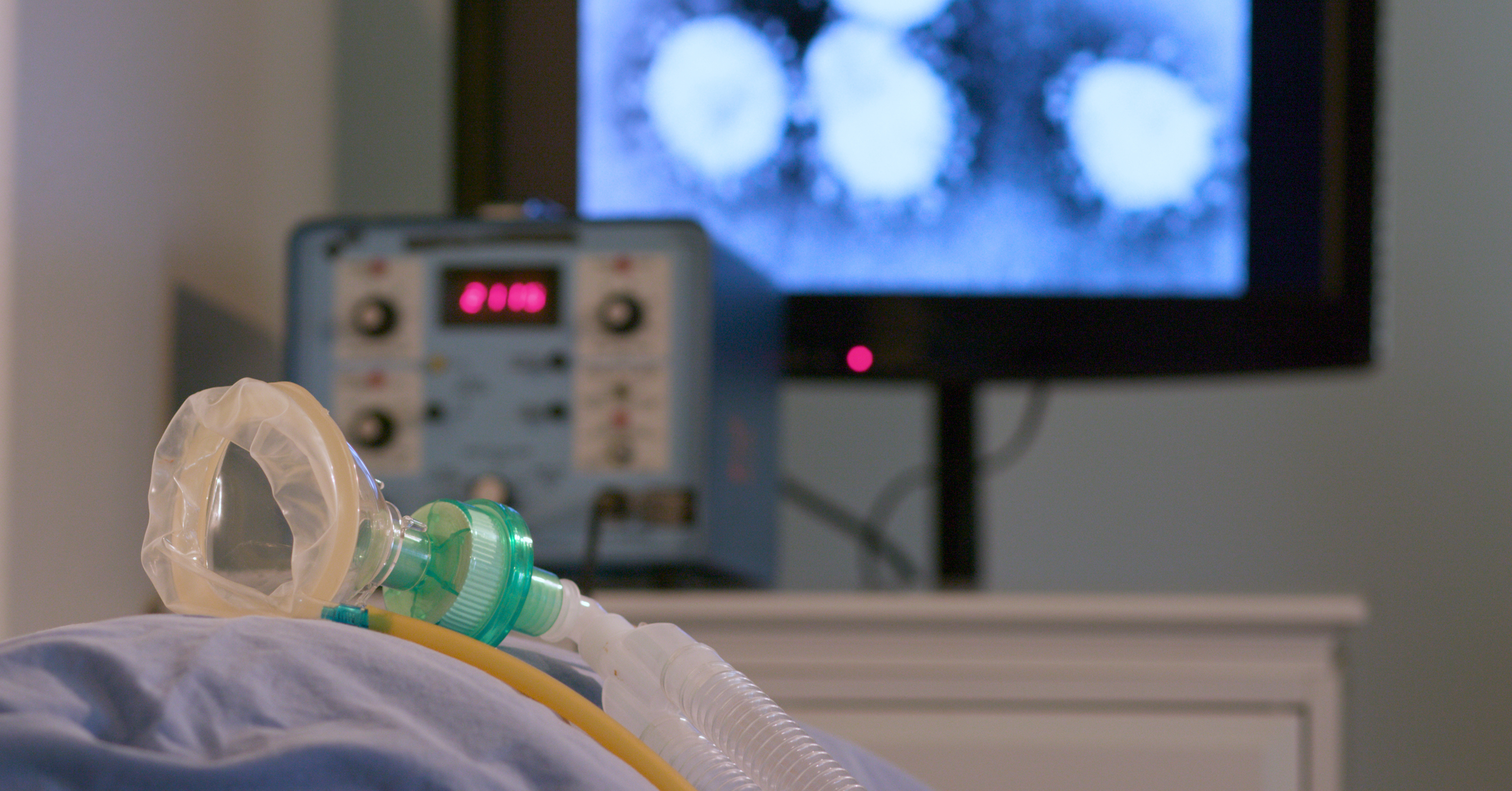 An oxygen mask in the foreground with monitors in the background.